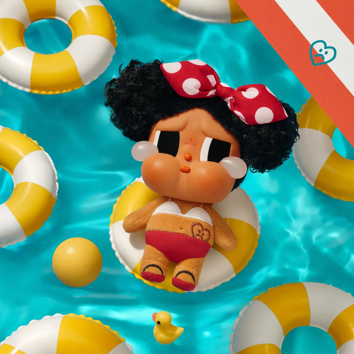 Toy character with a polka dot headband on an inflatable ring surrounded by pool toys in water. - little c land