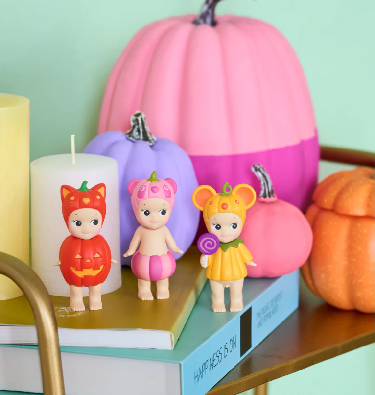 Colorful pumpkins and baby figurines on a shelf with a light green background